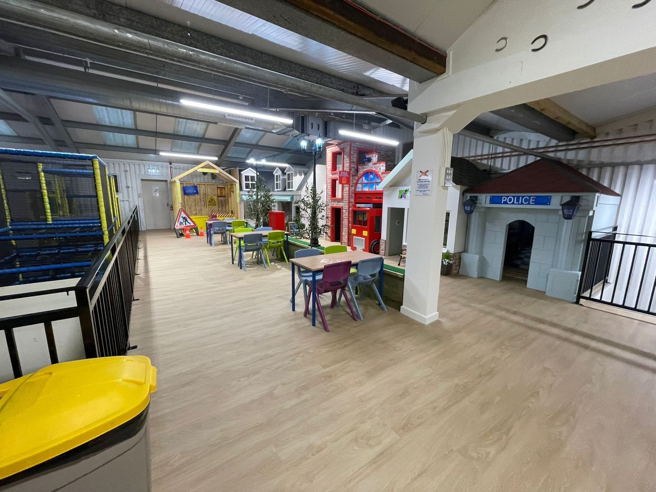 Wide view of the finished play barn with the role-play street, seating tables, police station and soft play frame
