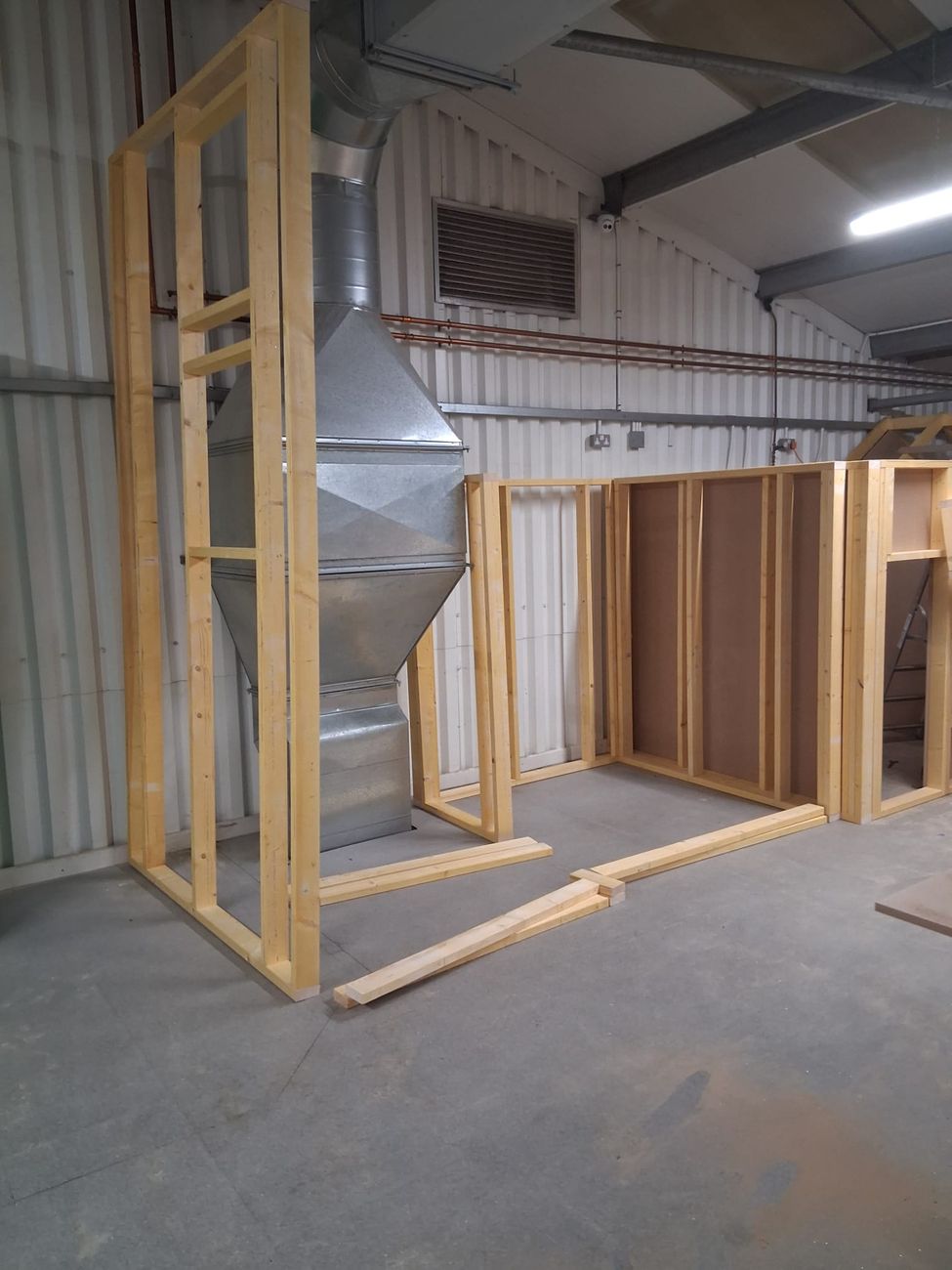 Stud frames for the play buildings standing squared up in the workshop