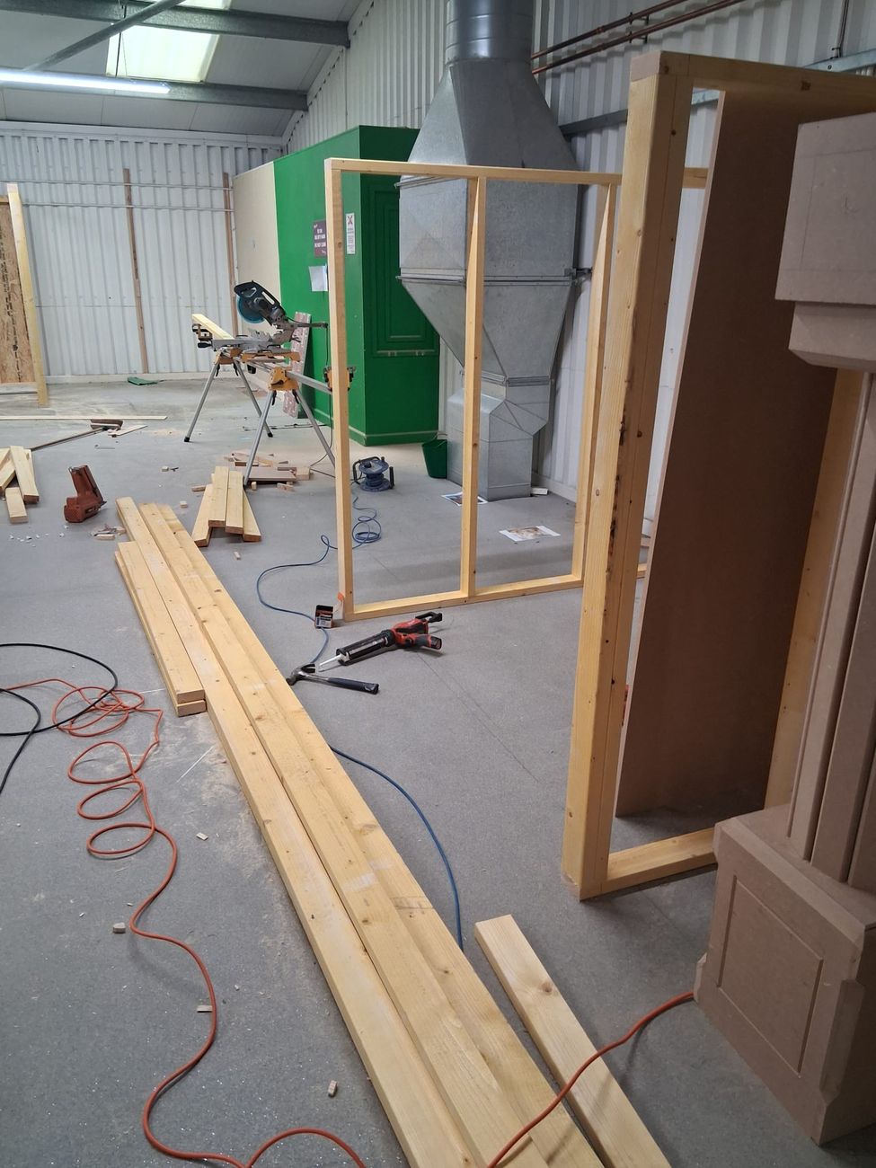 Timber lengths and cut panels laid out at the mitre saw ready for the play village build