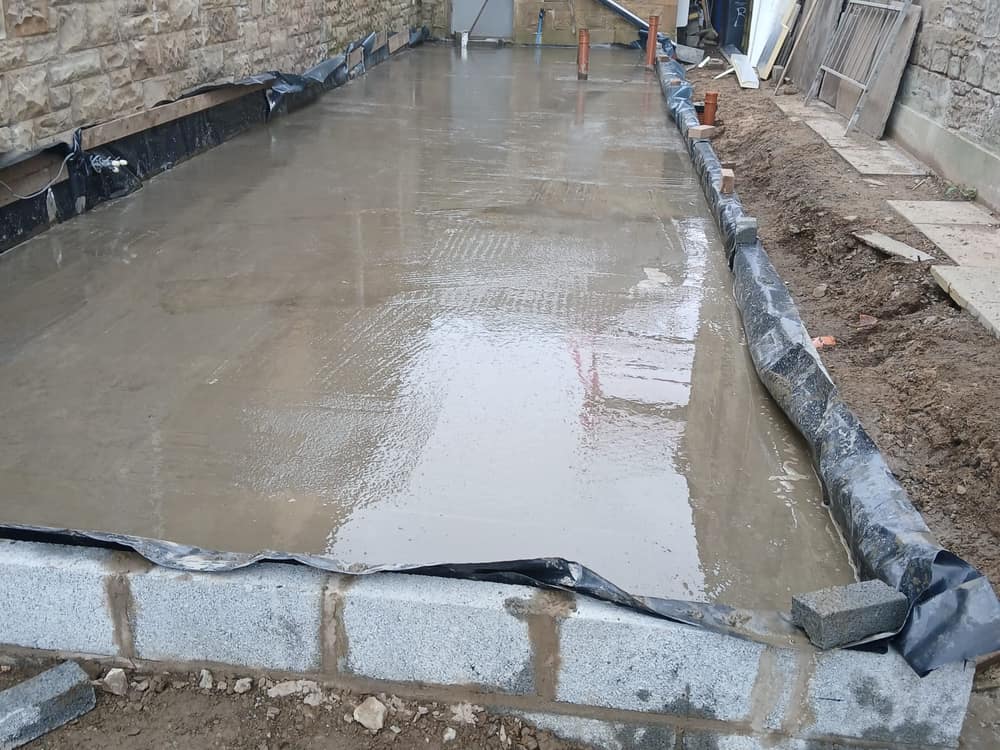 Freshly poured and floated concrete slab between two stone buildings