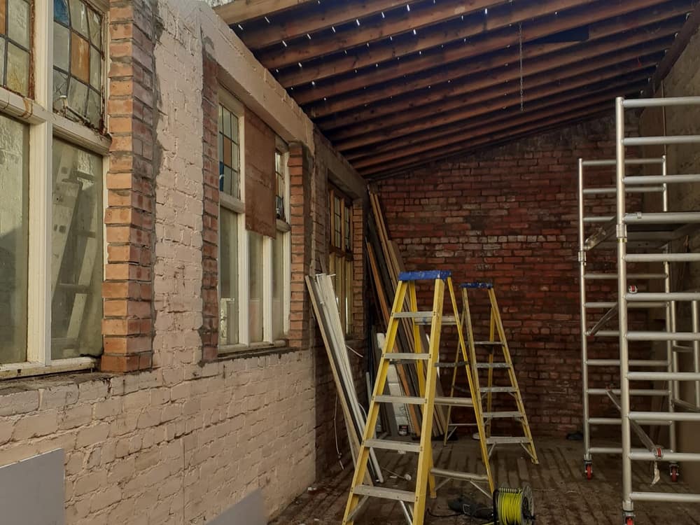 Exposed timber roof structure with access ladders during internal works