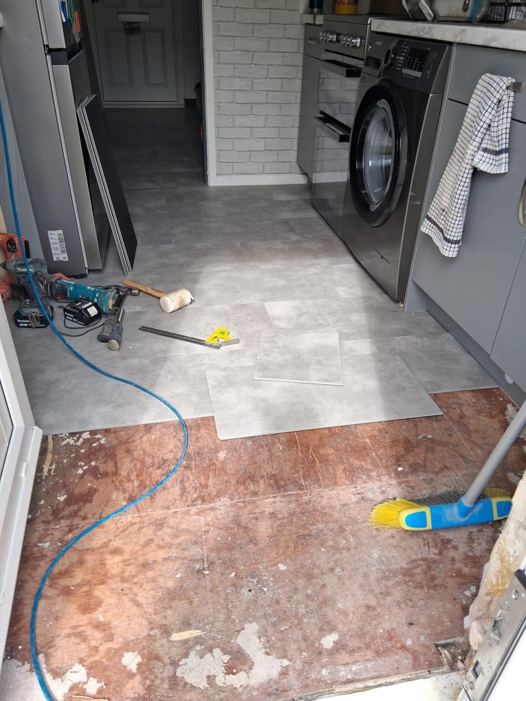 Grey vinyl floor tiles part-laid over a prepared subfloor during installation