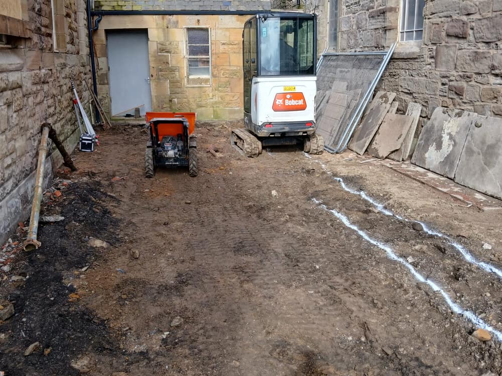 Excavated site with a mini digger and dumper ready for groundworks